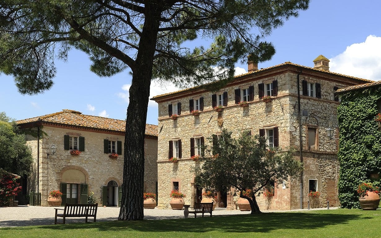 Stone villas with green shutters and flower boxes around the lawn at Borgo San Felice