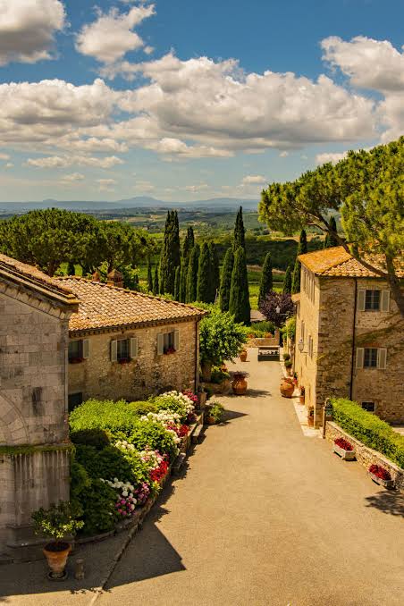 A lane of stone houses at Borgo San Felice leading to cypresses and the Tuscan hills
