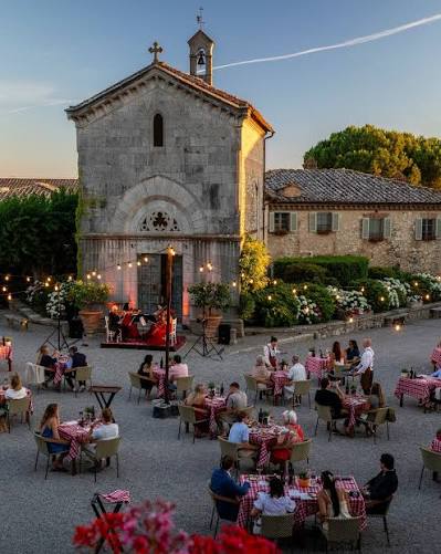 Dinner tables in the piazza at Borgo San Felice with live music outside the chapel at dusk