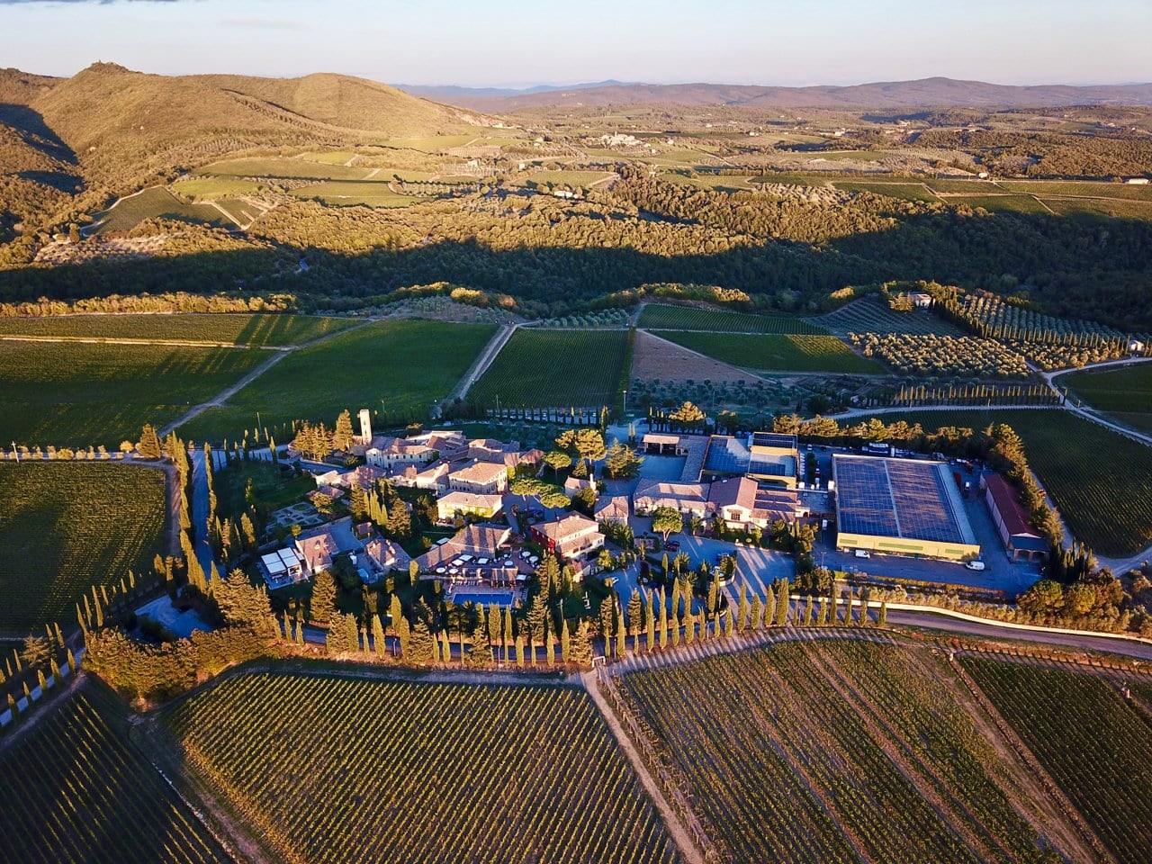 Borgo San Felice from above at golden hour, ringed by cypresses and Chianti vineyards